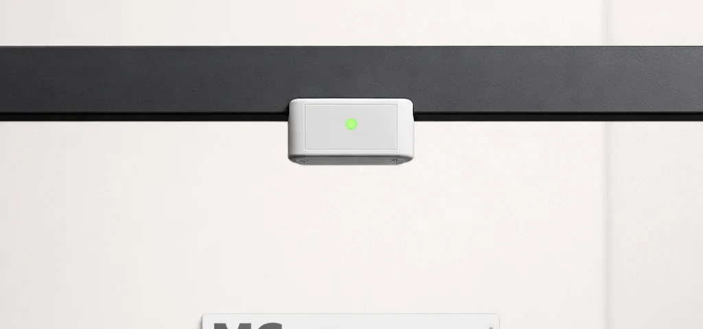 Un listón de persiana y un sensor de seguridad en un fondo blanco, mostrando eficiencia en sistemas de seguridad en persianas.